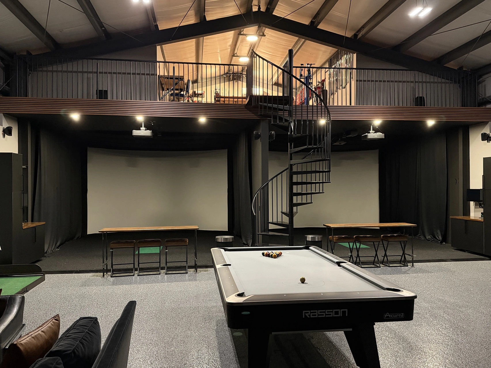Two indoor golf simulator bays behind a billiards table